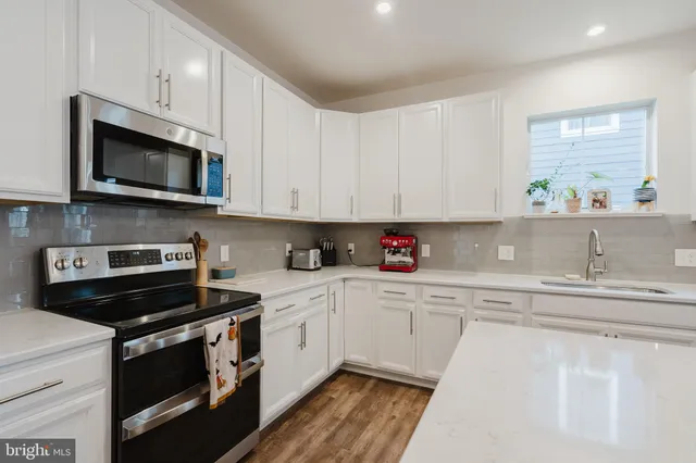 a kitchen with stainless steel appliances granite countertop a sink dishwasher a stove and a microwave oven with cabinets