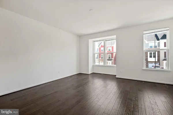 a view of an empty room with wooden floor and windows