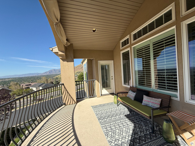 1562 Fairway Ridge Road Draper, UT 84020 - Photo 21 of 60 Covered balcony featuring a curved wrought iron railing, stucco exterior, and a mountain backdrop