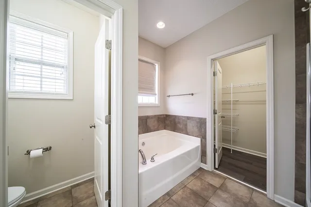 a spacious bathroom with a double vanity sink a large mirror and a bathtub