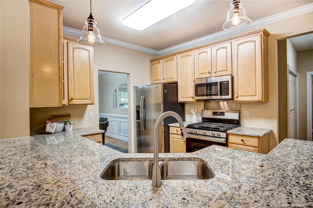 11121 Windgate Court Tega Cay, SC 29708 - Photo 14 of 44 a kitchen with stainless steel appliances granite countertop a sink a stove top oven a refrigerator a stove with dining table and chairs