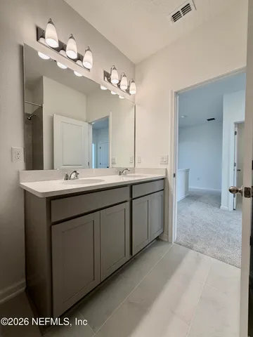 a bathroom with a double vanity sink a mirror and a shower