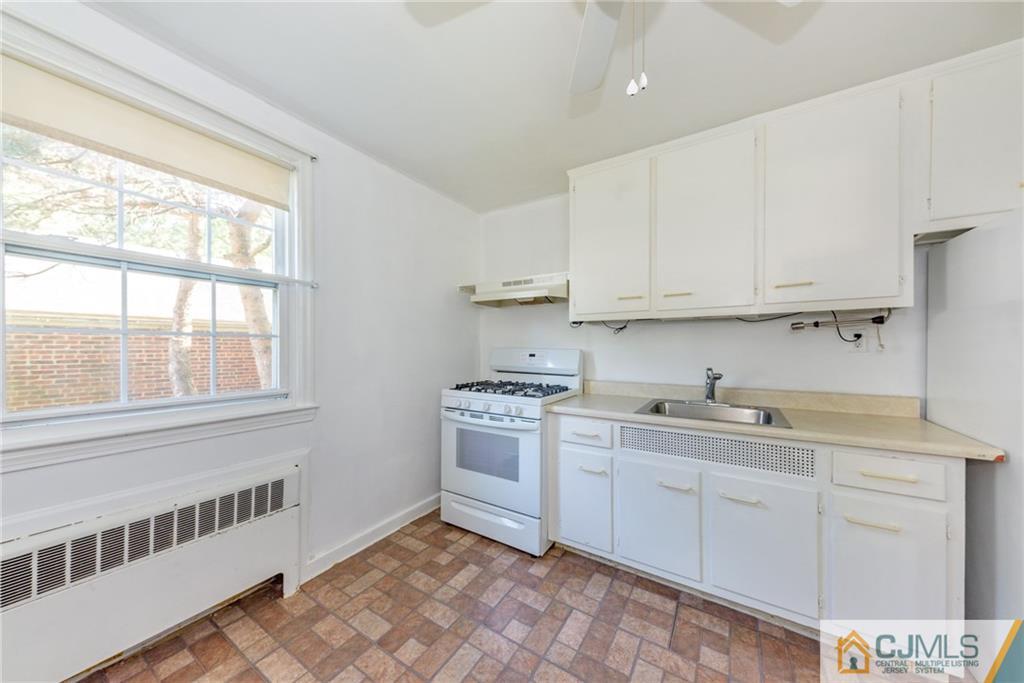 445 Morris Avenue, Unit D5 Springfield, NJ 07081 - Photo 8 of 21 a kitchen with white cabinets appliances and a window