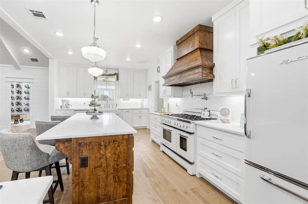 245 La Cresta Lane Perrin, TX 76486 - Photo 10 of 40 a kitchen with a stove a sink a kitchen island with wooden cabinets and floor