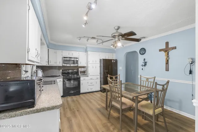 a kitchen with stainless steel appliances kitchen island granite countertop a table chairs and a refrigerator