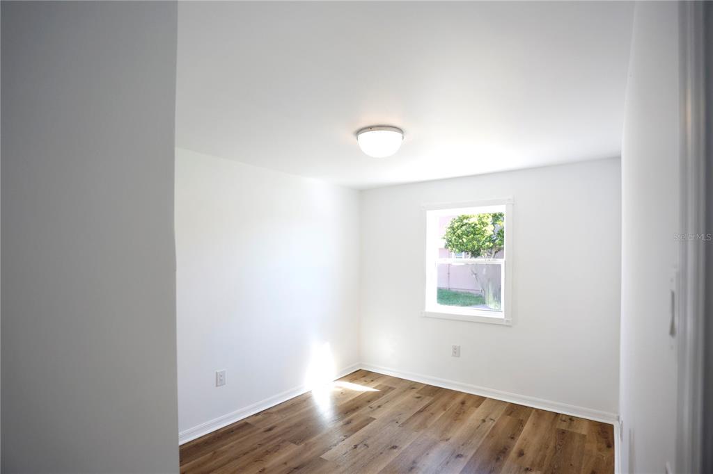 3194 Indian Gulf Lane Spring Hill, FL 34607 - Photo 14 of 38 a view of an empty room with wooden floor and a window