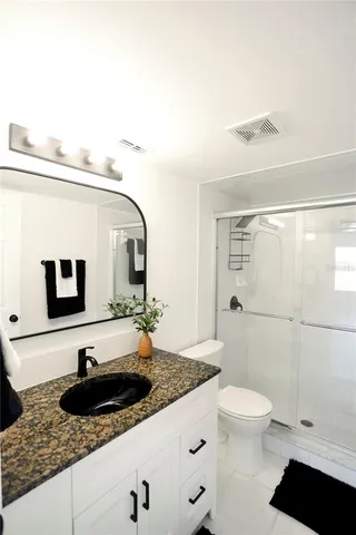 a bathroom with a granite countertop sink toilet and shower