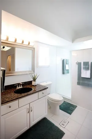a bathroom with a granite countertop sink and a toilet