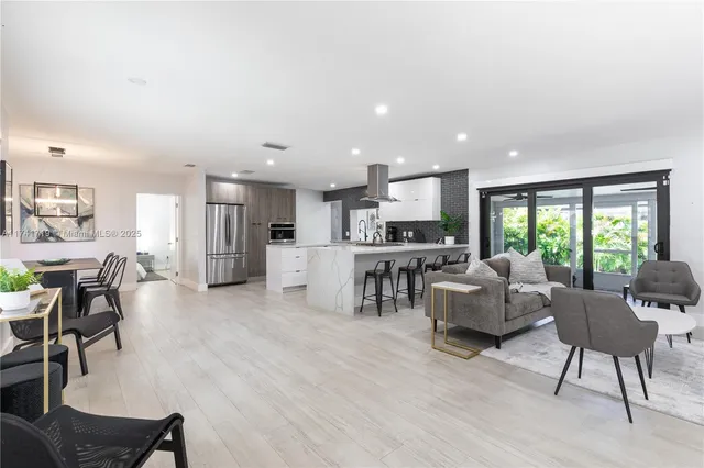 a living room with furniture and kitchen view with wooden floor