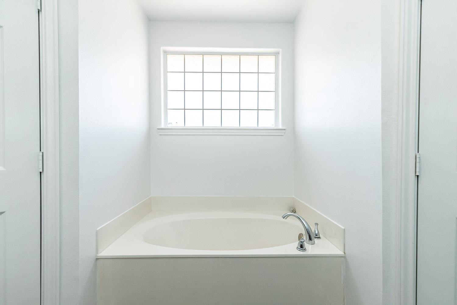 2006 100th Street Lubbock, TX 79423 - Photo 18 of 31 a white bath tub sitting next to a window