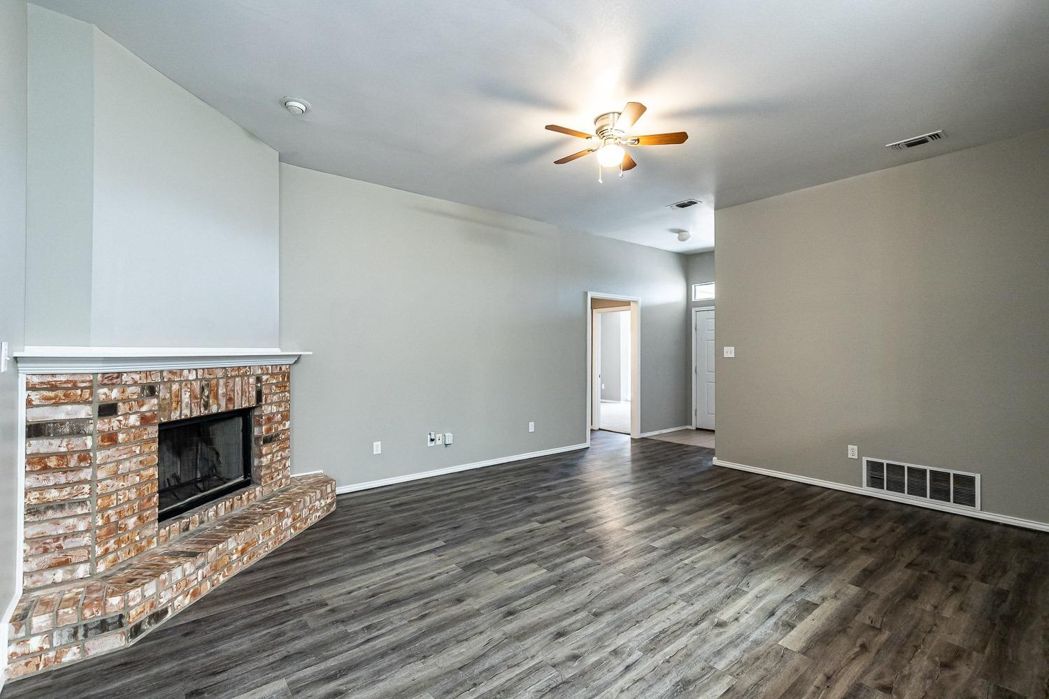 2006 100th Street Lubbock, TX 79423 - Photo 6 of 31 a view of an empty room with wooden floor fireplace and a window