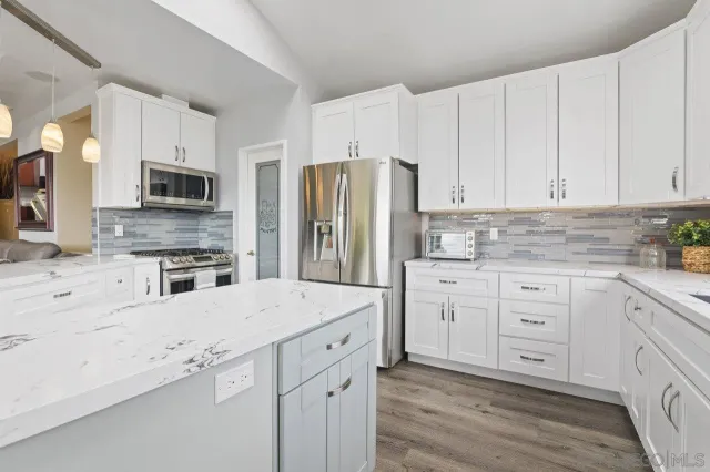 a kitchen with granite countertop white cabinets and stainless steel appliances