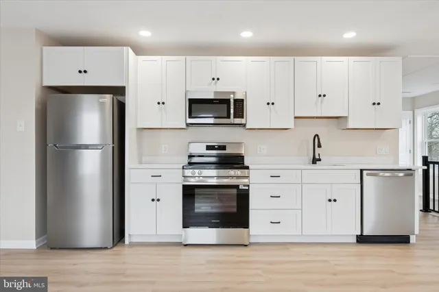 a kitchen with stainless steel appliances a refrigerator stove and white cabinets