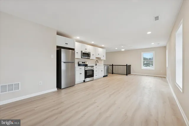 a large kitchen with a refrigerator a stove top oven a sink dishwasher and a refrigerator with wooden floor