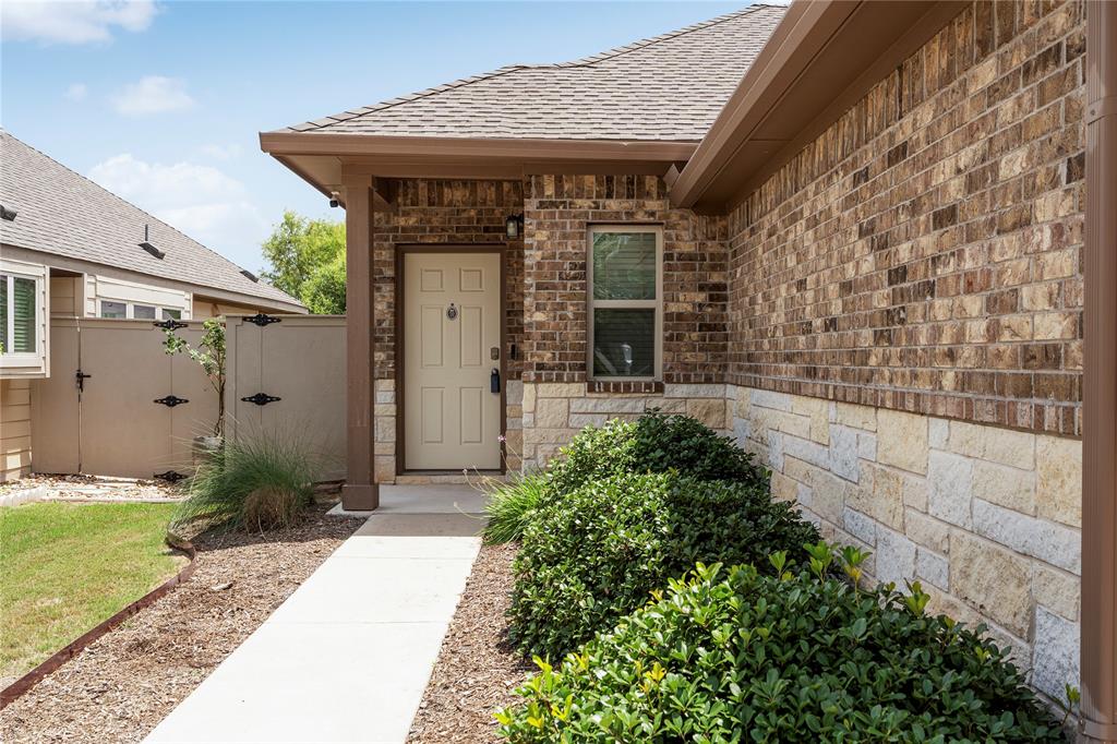 A welcoming concrete pathway leads past stone and brick accents straight to the front entry.