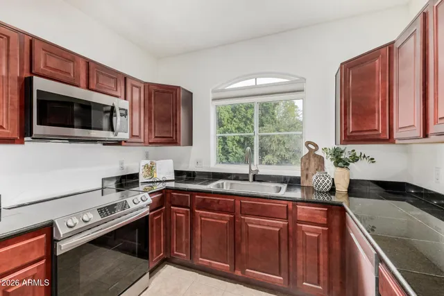 a kitchen with granite countertop a sink a stove a microwave and wooden cabinets