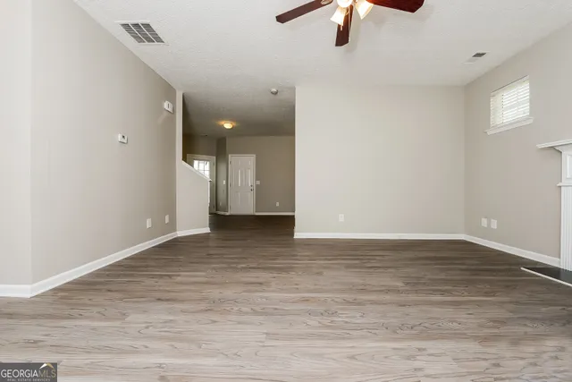 a view of an empty room with window and chandelier fan
