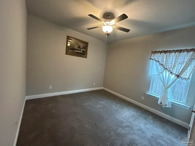 an empty room with a chandelier fan and windows