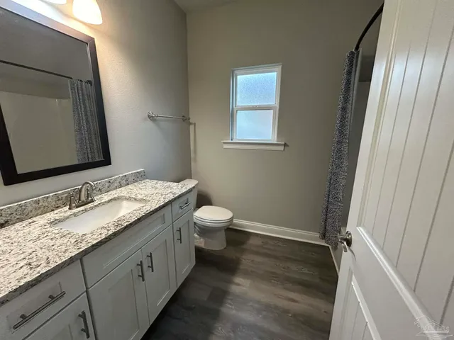 a bathroom with a granite countertop sink toilet and shower curtains