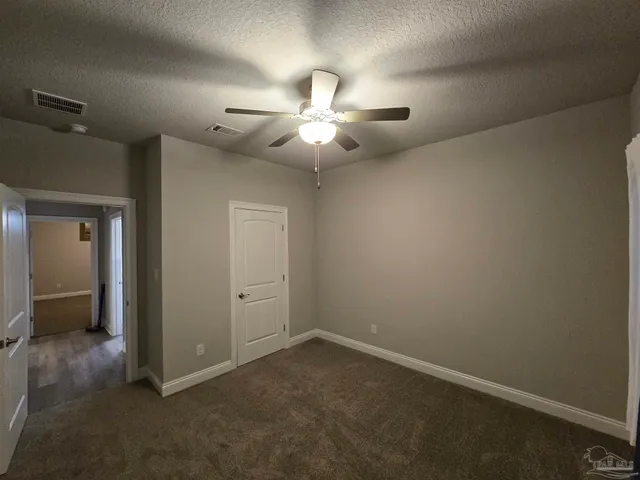 en empty room with ceiling fan and window