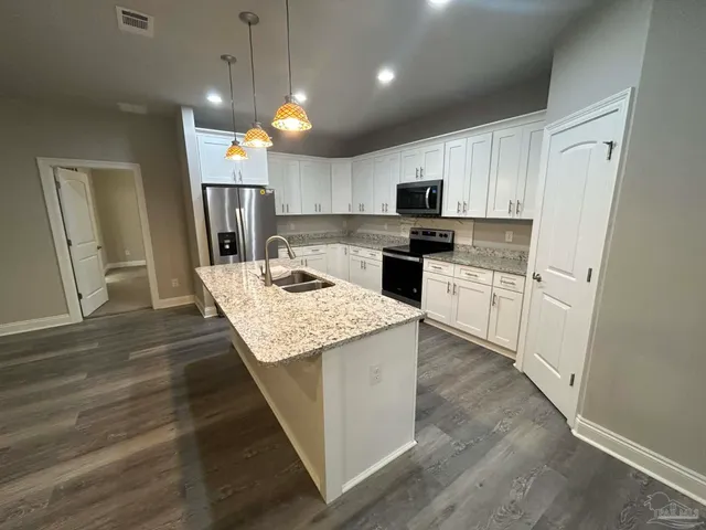 a kitchen with kitchen island granite countertop a sink a counter top space stainless steel appliances and cabinets
