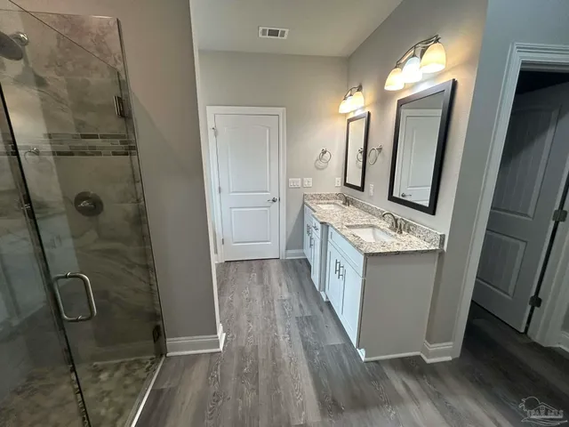 a bathroom with a granite countertop shower a sink and a mirror