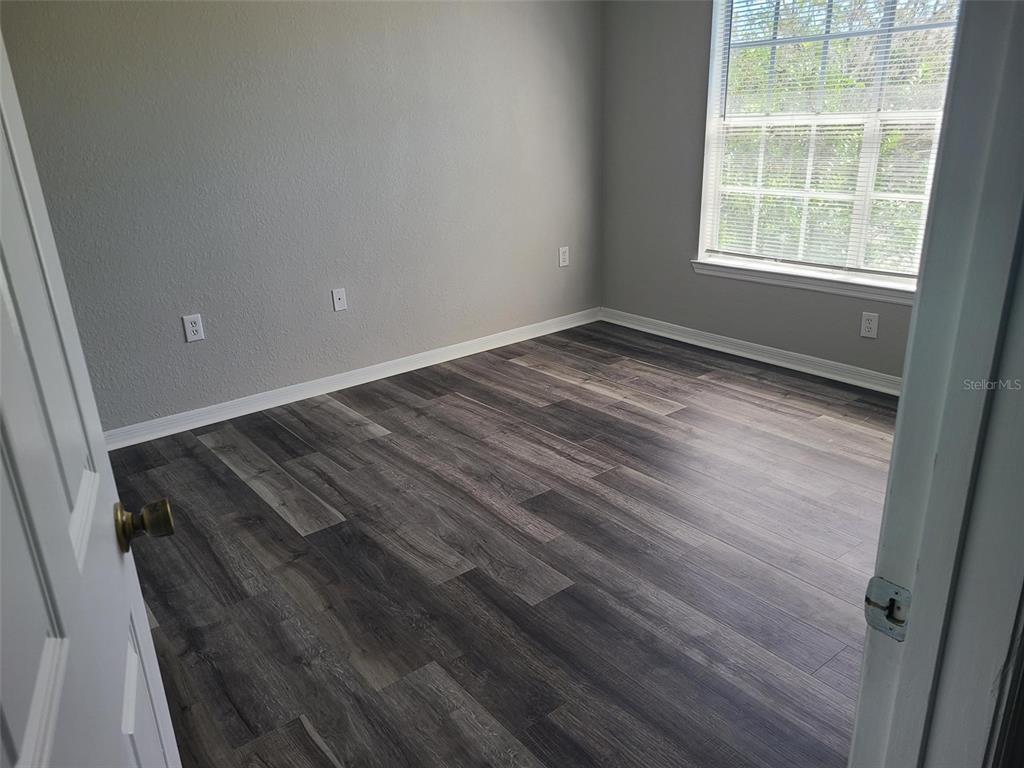8933 Manor Loop, Unit 202 Lakewood Ranch, FL 34202 - Photo 7 of 17 an empty room with wooden floor and windows