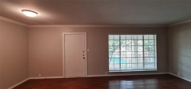 an empty room with wooden floor and windows with curtains