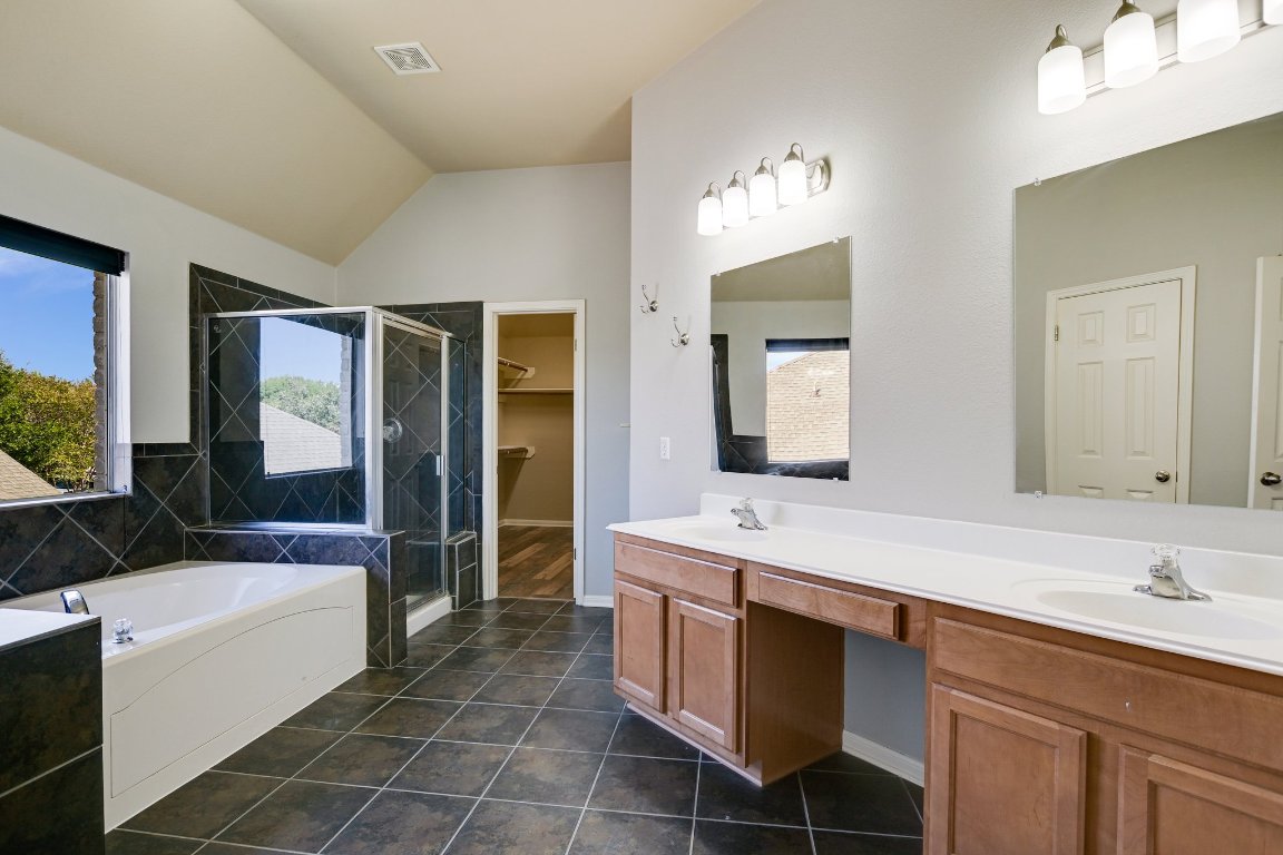 11705 Gold Run Cove Manor, TX 78653 - Photo 17 of 20 a spacious bathroom with a double vanity sink a large mirror and a bathtub
