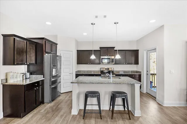 a kitchen with kitchen island granite countertop a sink stove and refrigerator with wooden floor