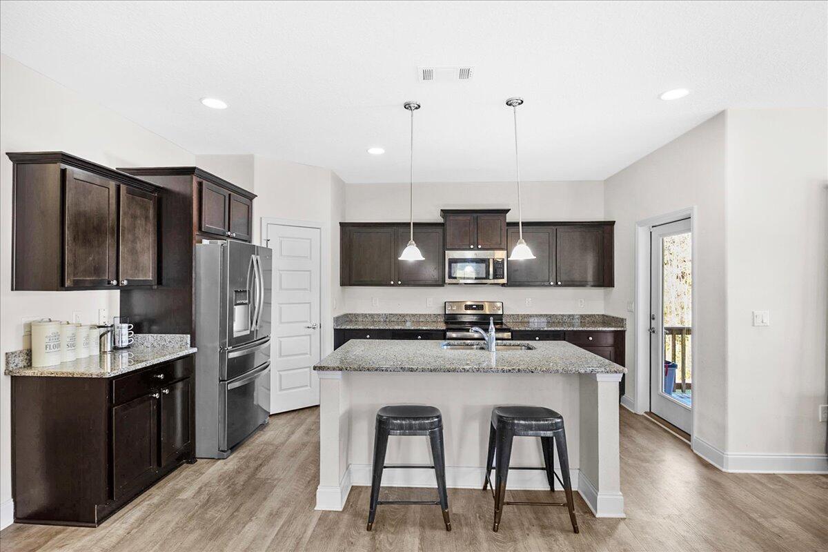 3030 Crown Creek Circle Crestview, FL 32539 - Photo 11 of 35 a kitchen with kitchen island granite countertop a sink stove and refrigerator with wooden floor