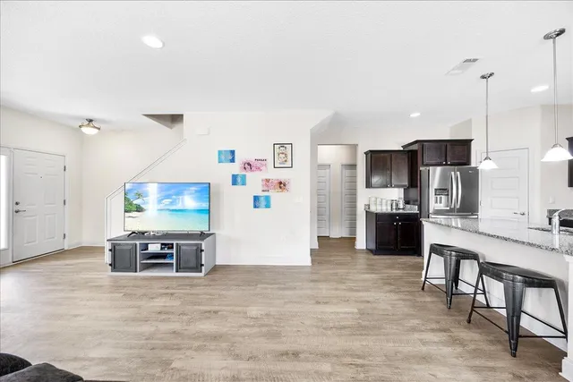 a living room with stainless steel appliances furniture and a flat screen tv