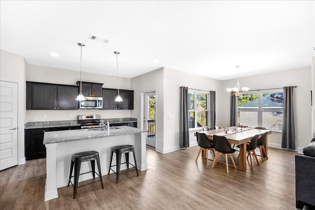 3030 Crown Creek Circle Crestview, FL 32539 - Photo 8 of 35 a kitchen with stainless steel appliances granite countertop a stove a refrigerator a kitchen island a dining table and chairs with wooden floor