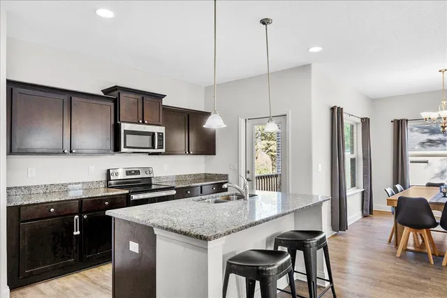 a kitchen with stainless steel appliances granite countertop a kitchen island hardwood floor sink stove dining table and chairs