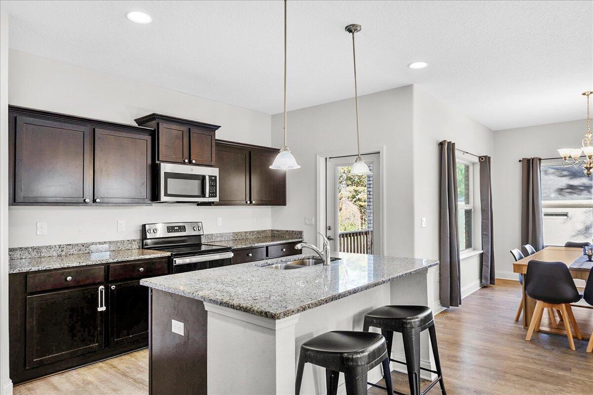3030 Crown Creek Circle Crestview, FL 32539 - Photo 10 of 35 a kitchen with stainless steel appliances granite countertop a kitchen island hardwood floor sink stove dining table and chairs