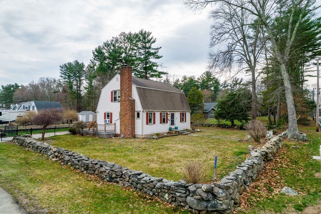 210 Hathaway Road Acushnet, MA 02743 - Photo 1 of 34 a house that is sitting in the grass with large trees and plants