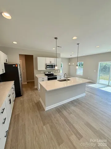 a large white kitchen with kitchen island a sink a stove a refrigerator and a cabinets