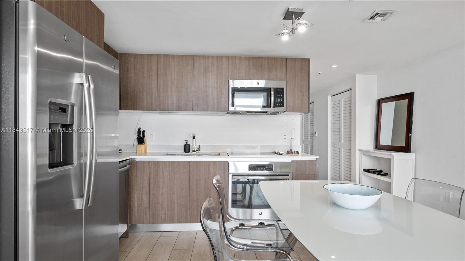 1600 Southwest 1st Avenue, Unit 1104 Miami, FL 33129 - Photo 5 of 22 a kitchen with stainless steel appliances a dining table chairs and stove