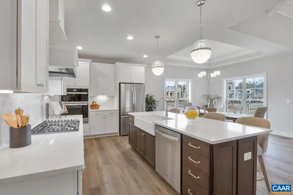 a kitchen with stainless steel appliances kitchen island granite countertop a dining table chairs refrigerator and microwave
