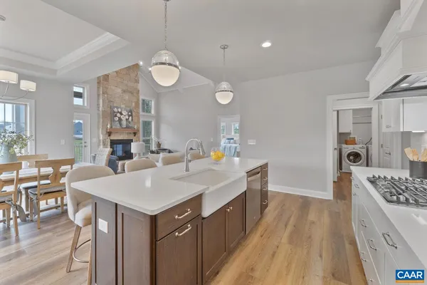 a kitchen that has a table chairs in it wooden floors and white cabinets