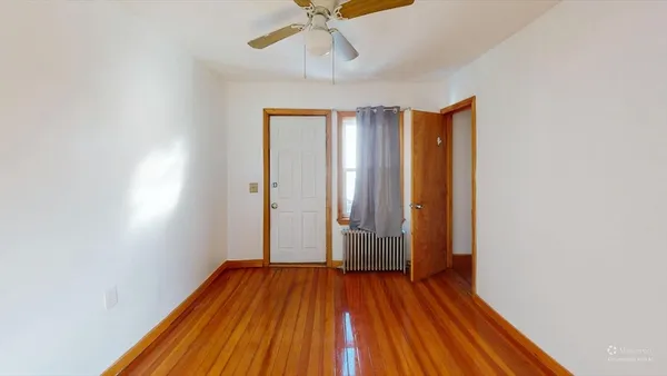 an empty room with wooden floor fan and windows