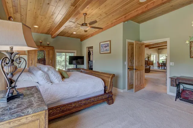 a spacious bedroom with a bed a table and potted plant