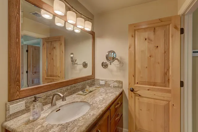 a bathroom with a granite countertop sink a toilet a mirror and shower