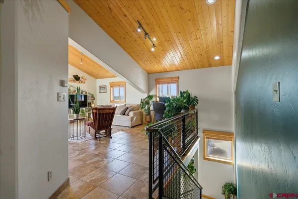 a living room with furniture a flat screen tv and floor to ceiling window
