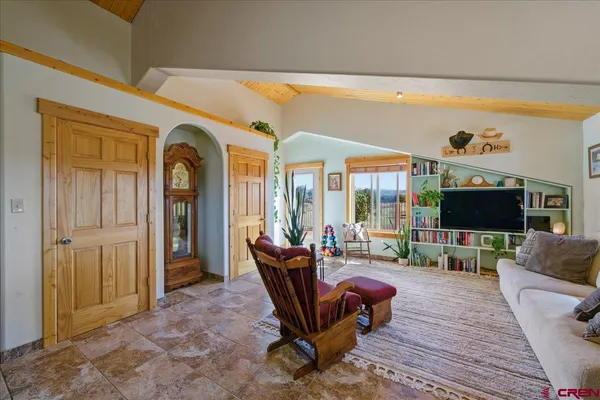 a living room with furniture a flat screen tv and floor to ceiling window