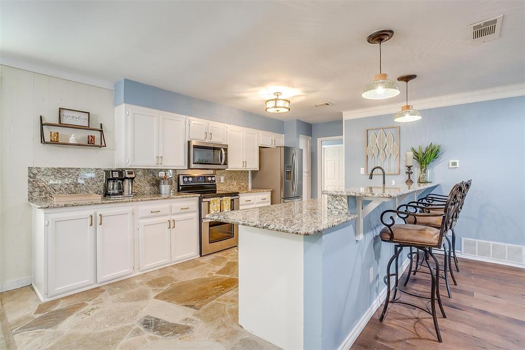 520 Deer Trail Gordon, TX 76453 - Photo 7 of 40 a kitchen with stainless steel appliances granite countertop a stove a sink a microwave a dining table and chairs with wooden floor