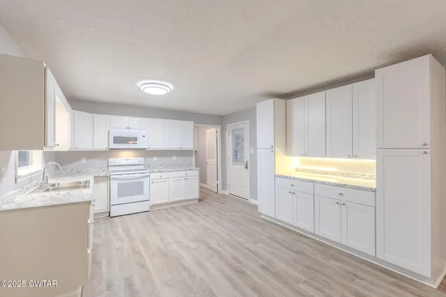 a large white kitchen with a sink wooden floor and a window