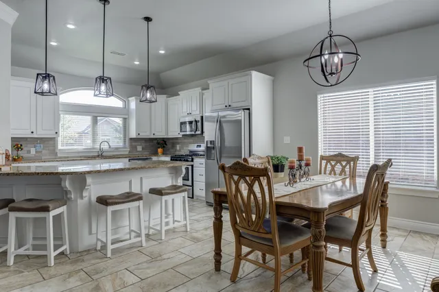 a kitchen with stainless steel appliances granite countertop a kitchen island a table and chairs
