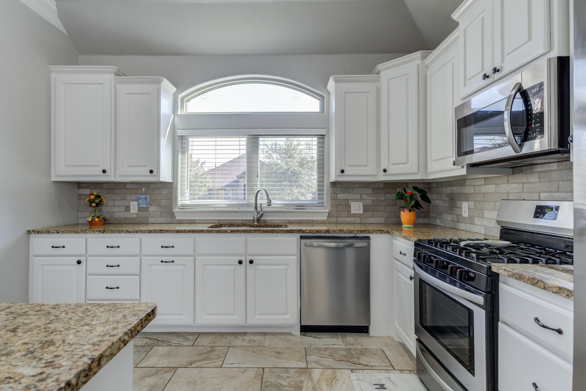 6306 87th Street Lubbock, TX 79424 - Photo 19 of 47 a kitchen with granite countertop white cabinets stainless steel appliances and a window