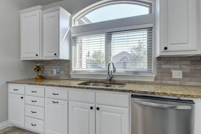 a kitchen with granite countertop white cabinets and window